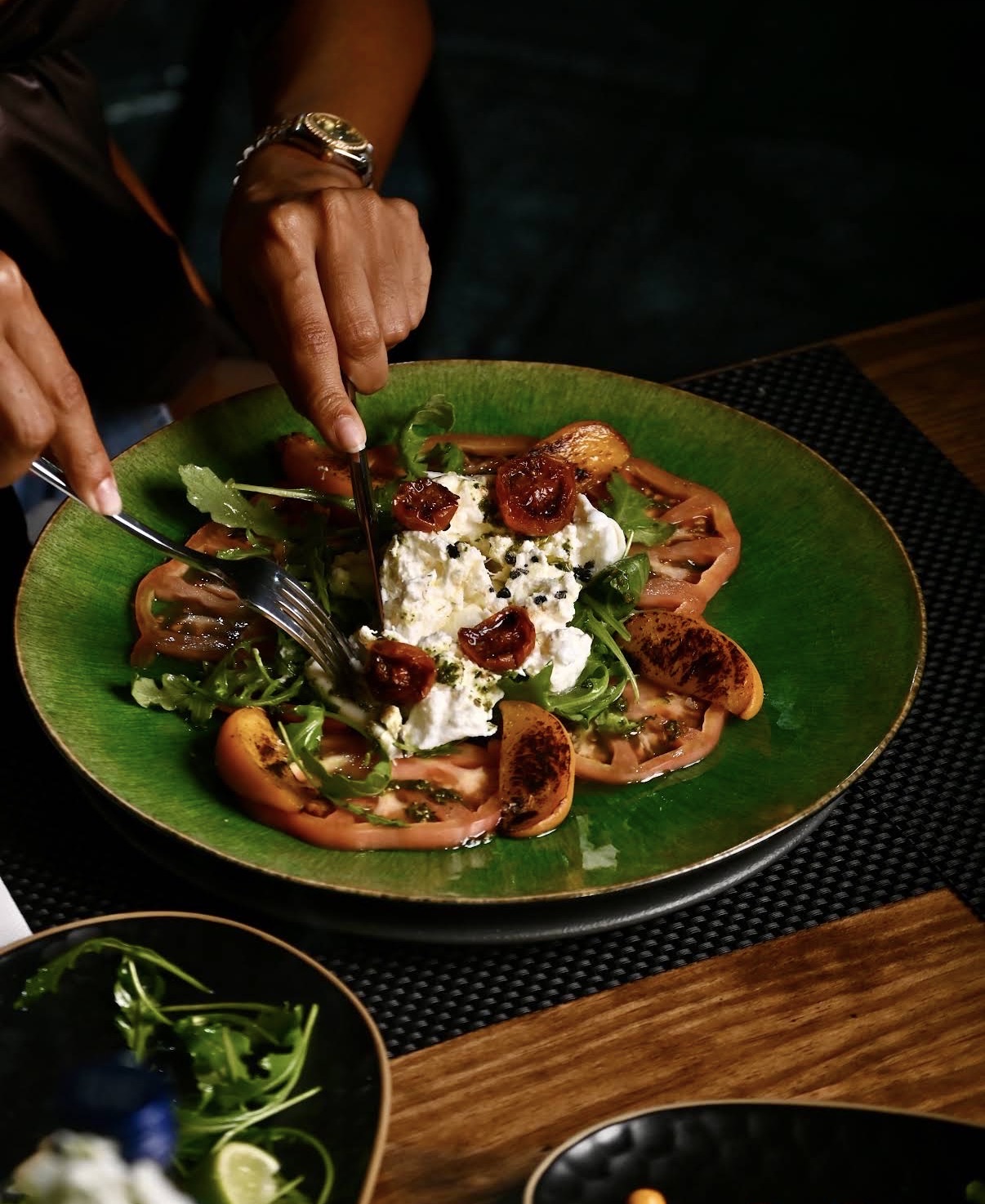 Diner cutting into a plated burrata and tomato dish at Mangut Banus in Marbella