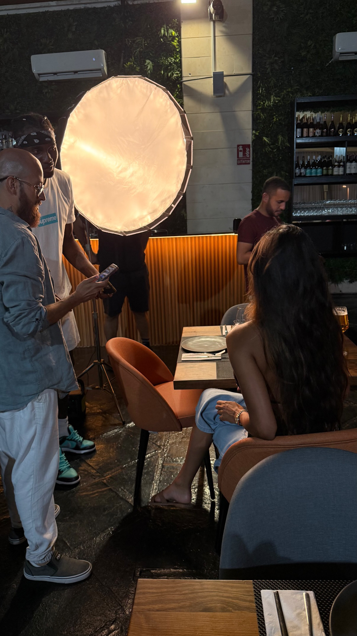 Production crew lighting a seated guest during a Mangut Banus restaurant shoot