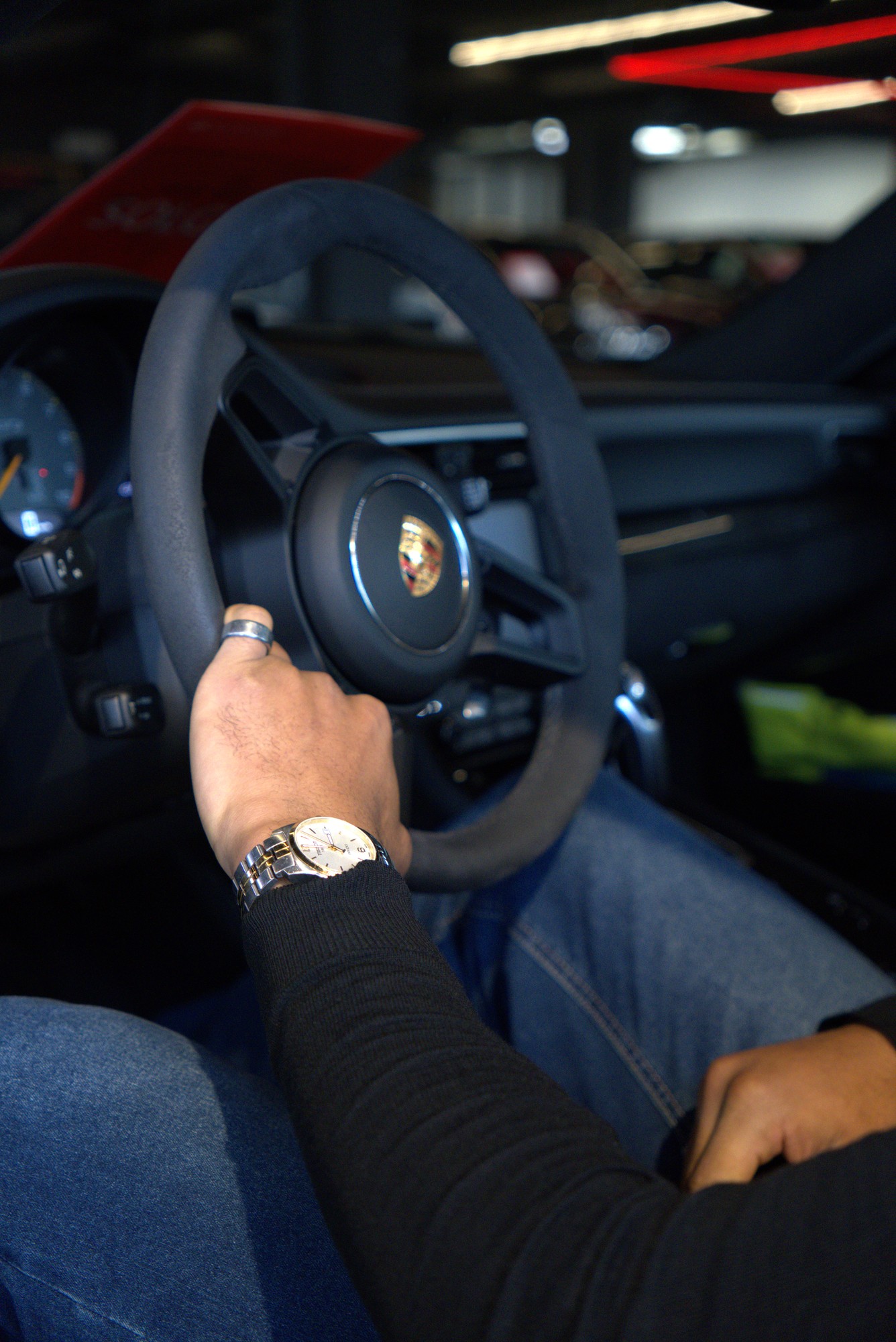 Driver holding a Porsche steering wheel inside a dark car interior at T.A Auto